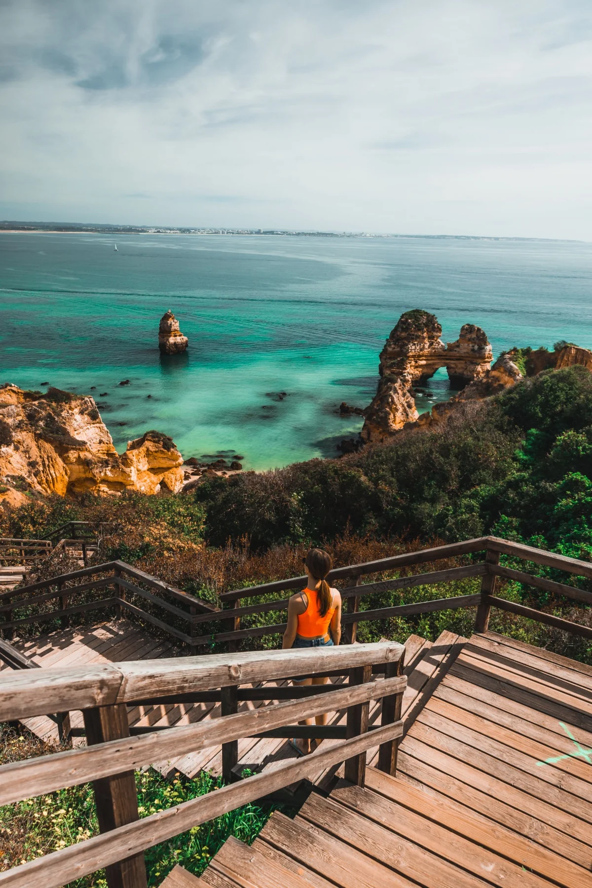 Wooden stairs descending toward a beach between coastal rocks