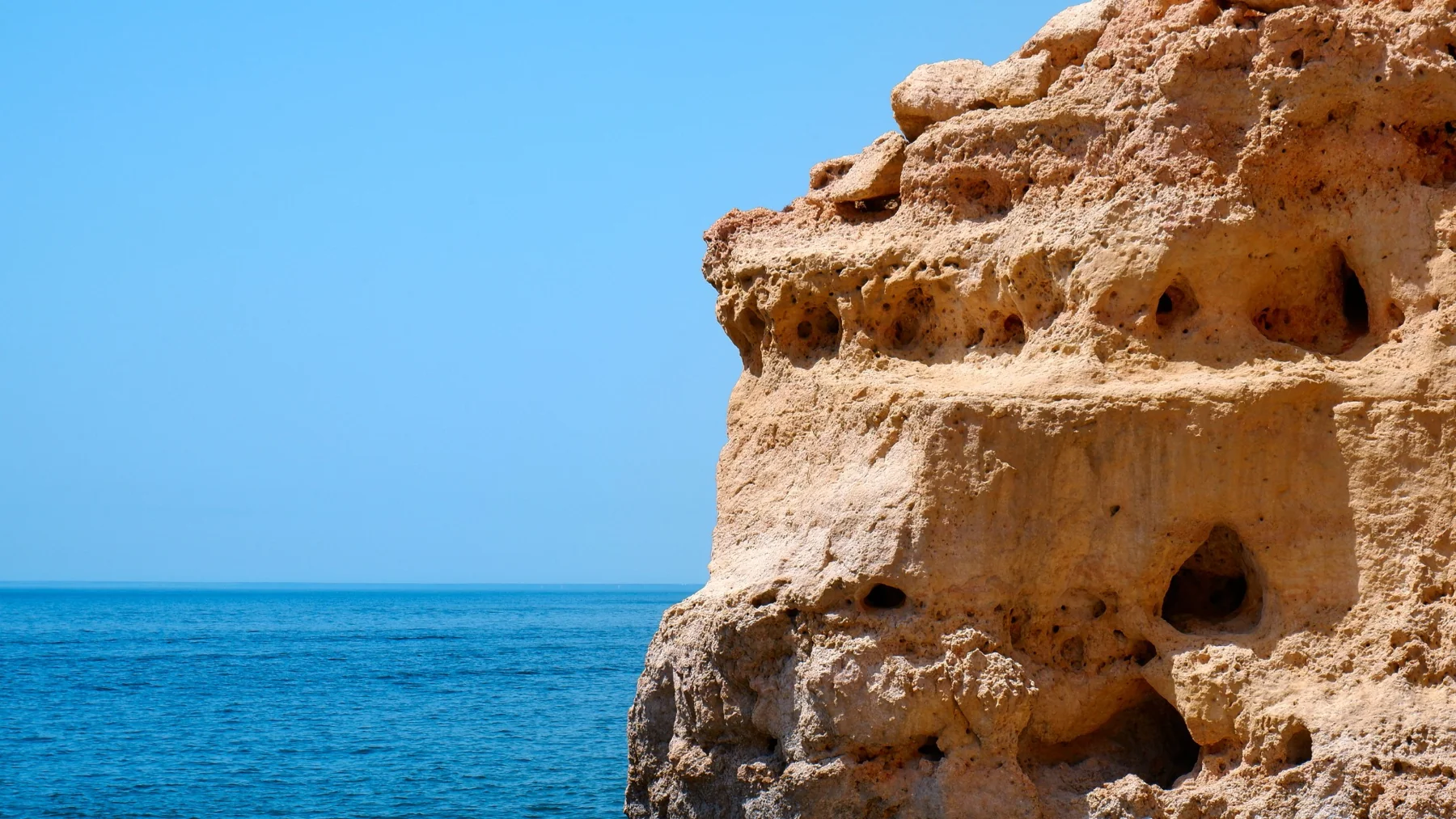Golden coastal cliff above blue water