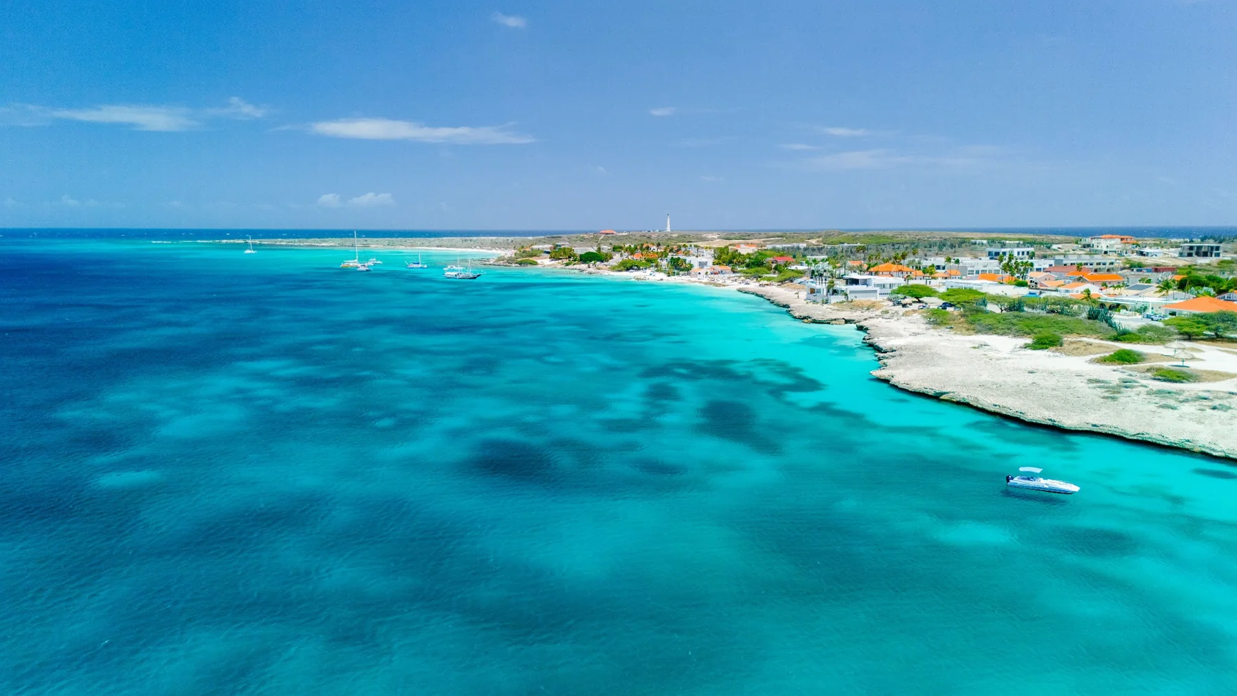 Aerial view of a turquoise bay, boats and low coastal buildings