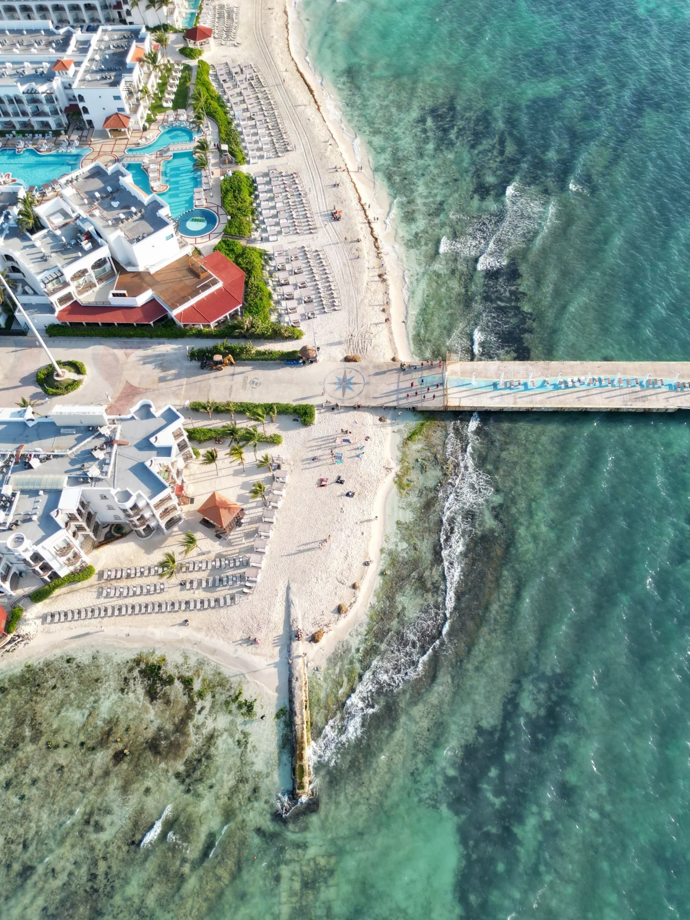 Aerial view of a coastal town and pier beside turquoise water
