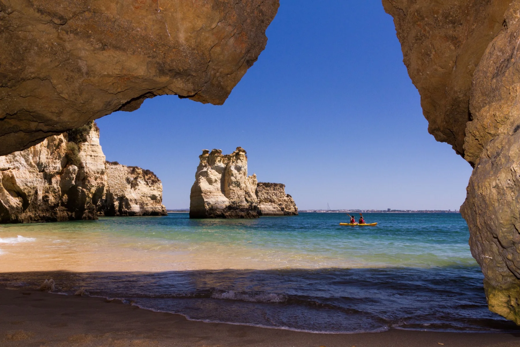 Golden rock formations framing the sea through a coastal opening