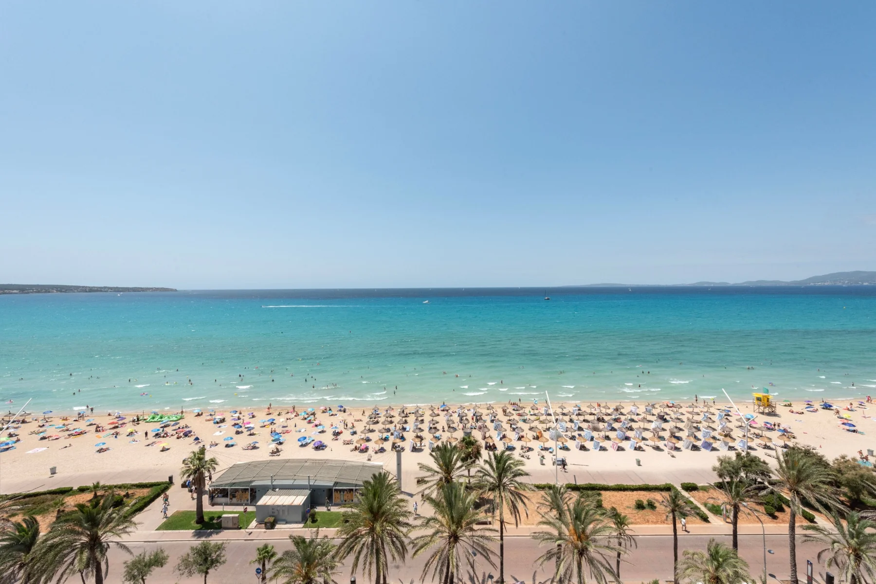 Rows of beach loungers beside blue sea and a sandy shore