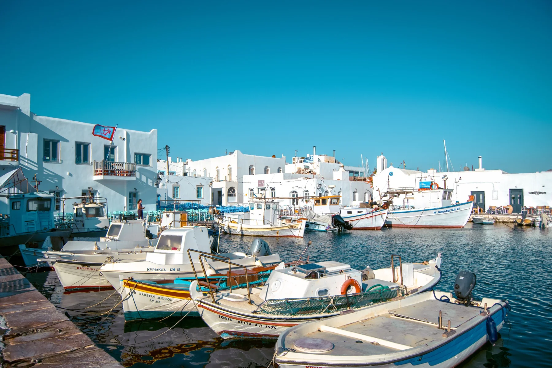 Fishing boats beside a waterfront of white buildings
