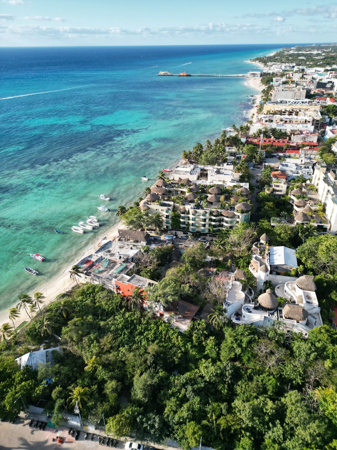 Aerial view along a sandy coastline with buildings and small boats
